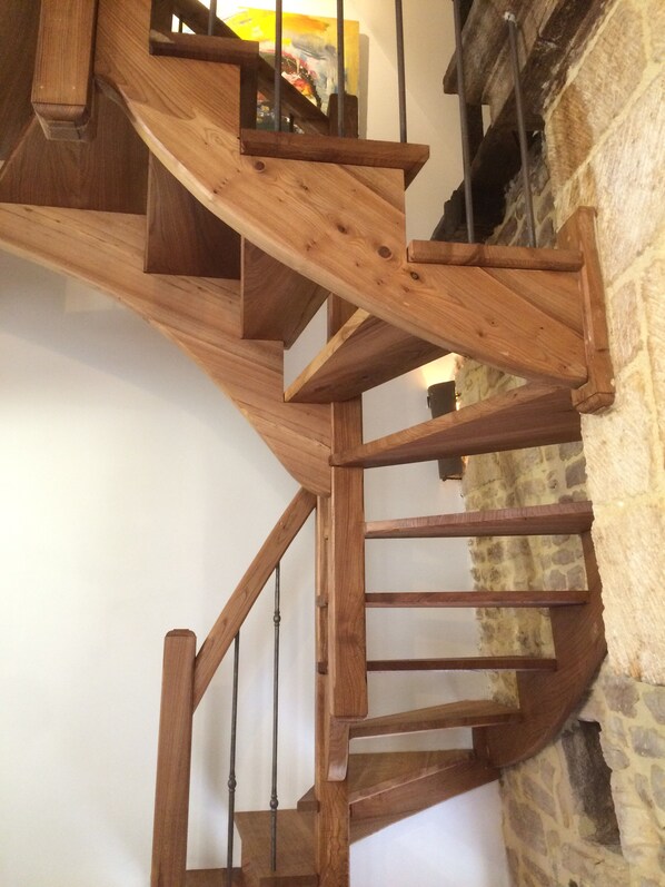 Una escalera en espiral de madera con un fondo de pared de piedra.