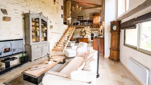 A spacious living room with a white sofa, wooden coffee table, and a television. A staircase leads to an upper level. - Casa Guillarmou - Heated Pool & Spa - Splendid (Castelnau-de-Montmiral)