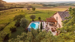 A villa with a swimming pool, outdoor seating, and a view of rolling hills. - Casa Guillarmou - Heated Pool & Spa - Splendid (Castelnau-de-Montmiral)