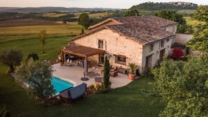 A stone house with a pool, outdoor seating, and a view of the countryside. - Casa Guillarmou - Heated Pool & Spa - Splendid (Castelnau-de-Montmiral)