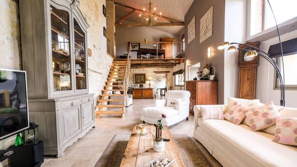 A spacious living room with a white sofa, a wooden coffee table, and a staircase leading to an upper level. - Casa Guillarmou - Heated Pool & Spa - Splendid (Castelnau-de-Montmiral)