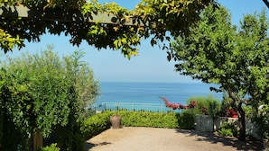 A gravel pathway leading to a coastal view with a metal railing and greenery.