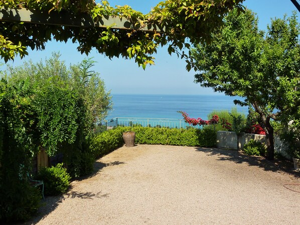 A gravel pathway leading to a coastal view with a metal railing and greenery.