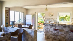 A kitchen with a tiled backsplash, a refrigerator, a dining area with a table and chairs, and a bar area with stools.