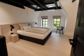 Een slaapkamer met een groot bed, een houten hoofdbord, een klein nachtkastje en een stoel.
