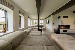 Una sala de estar moderna con un sofá grande, una chimenea y ventanas amplias.