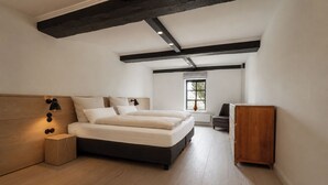 Ein modernes Schlafzimmer mit einem großen Bett, einem Nachttisch aus Holz, einer Kommode und einem Fenster mit Jalousien.