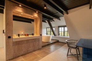 Een moderne badkamer met een houten wastafelmeubel, een grote spiegel en een bad.