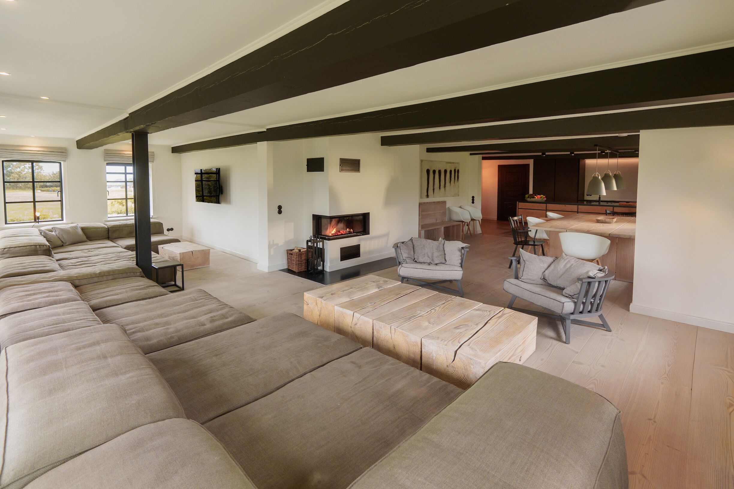 A spacious living area with a fireplace, a long sofa, and a dining area with chairs.