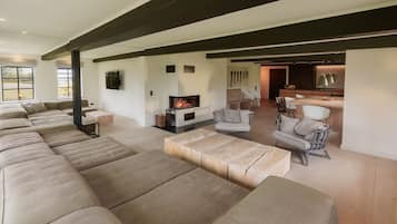 A spacious living area with a fireplace, a long sofa, and a dining area with chairs.