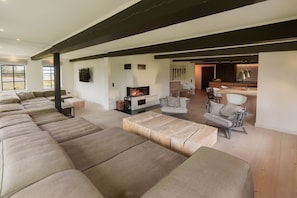 Un amplio salón con chimenea, un sofá grande y una zona de comedor con sillas.