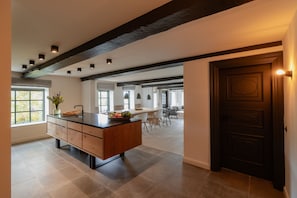 Una cocina moderna con una isla central, armarios empotrados y una viga de techo oscura.