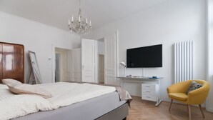 Un dormitorio con cama, escritorio, silla, televisión y candelabro.