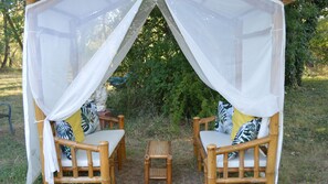 A covered seating area with two chairs and a small table, surrounded by greenery. - Cottage 2 to 5 people (Saint-Clément)