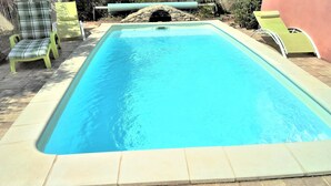 A rectangular swimming pool with a stone arch entrance, surrounded by a tiled deck. - Cottage 2 to 5 people (Saint-Clément)