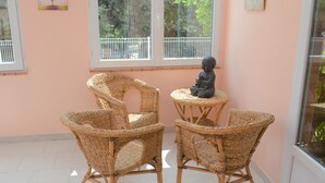 A room with two wicker chairs, a small statue, and a window with a view of trees. - Cottage 2 to 5 people (Saint-Clément)