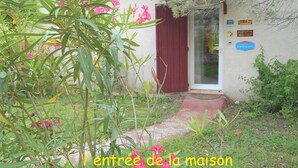 A quaint house with a red door, a small porch, and a garden with pink flowers. - Cottage 2 to 5 people (Saint-Clément)