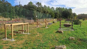 An outdoor exercise area with wooden structures and a chain-link fence. - Cottage 2 to 5 people (Saint-Clément)