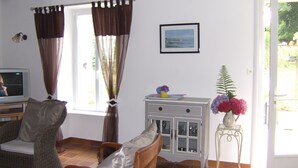 A living room with a television, wicker furniture, a cabinet with glass doors, and a window with curtains. - House in a pastoral setting: 2 or 4 people (Douarnenez)