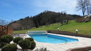 A rectangular swimming pool with a wooden deck and a wooden fence surrounding it. - Cottage Le Meixzoté (Ferdrupt)