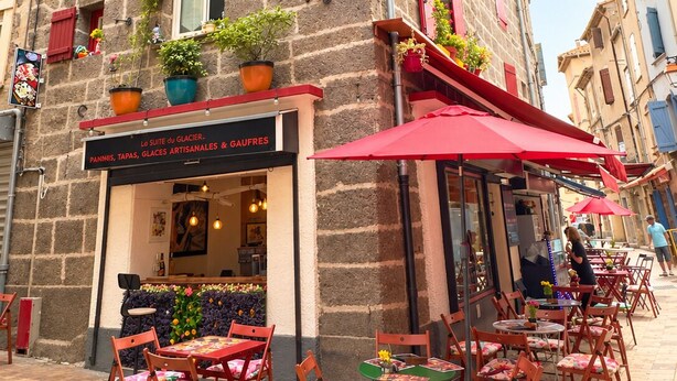 A stone building with a café terrace featuring outdoor seating. - Village apartment  (Agde)