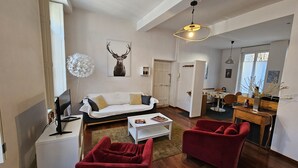 Un salon moderne avec un canapé blanc, des fauteuils rouges et un coin repas comprenant une table et des chaises.