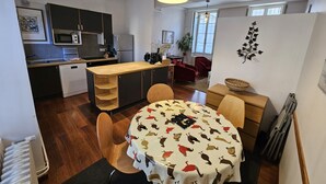 Une cuisine compacte dotée d’appareils électroménagers modernes, un coin repas avec une nappe à motifs et un espace salon confortable.