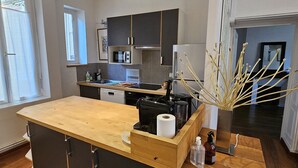 A modern kitchen with a wooden island, built-in appliances, and a view to the living area. - Le Pasteur, the perfect place in the historical centre of Dijon (up to 4 guests) (Dijon)