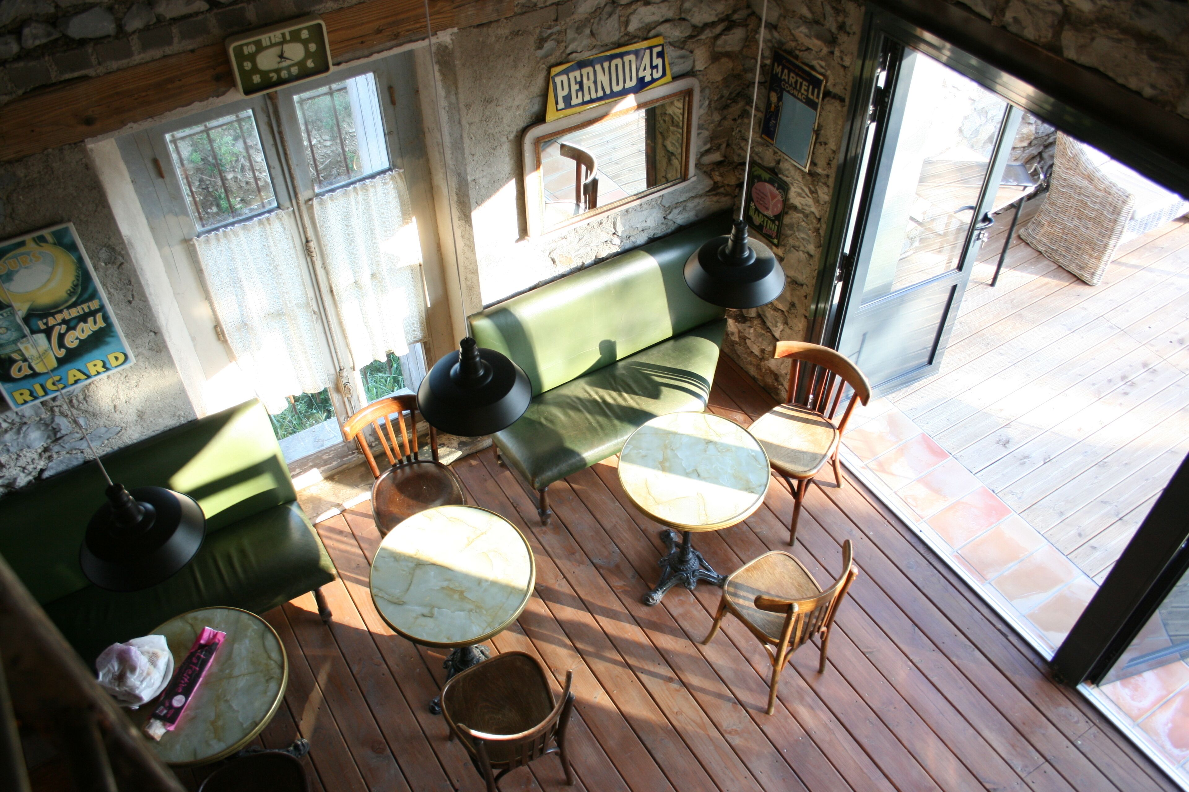 A cozy interior with a green sofa, wooden tables, and a stone wall.