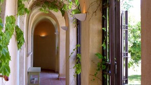 Un couloir orné d’arches, doté d’un sol carrelé et agrémenté de plantes vertes.