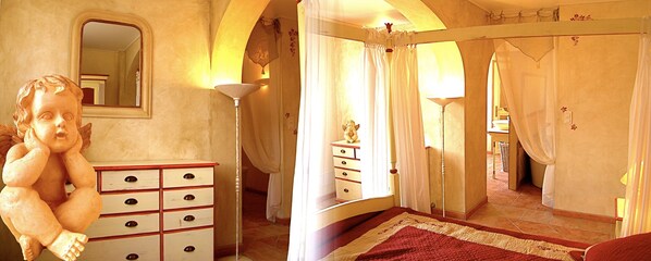Ein Schlafzimmer mit einem Bett, einem Schminktisch und einer Cherubstatue.