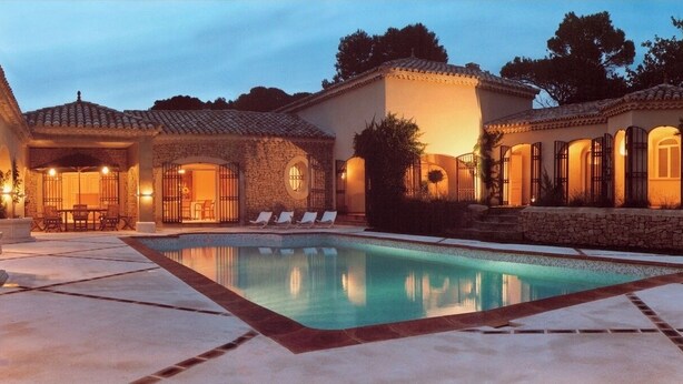 Une villa de luxe dotée d’une piscine, d’une architecture en pierre et d’espaces extérieurs aménagés pour se détendre.