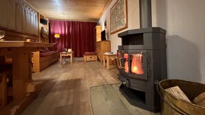 Ett mysigt rum med en vedeldad kamin, trämöbler och en röd gardin.