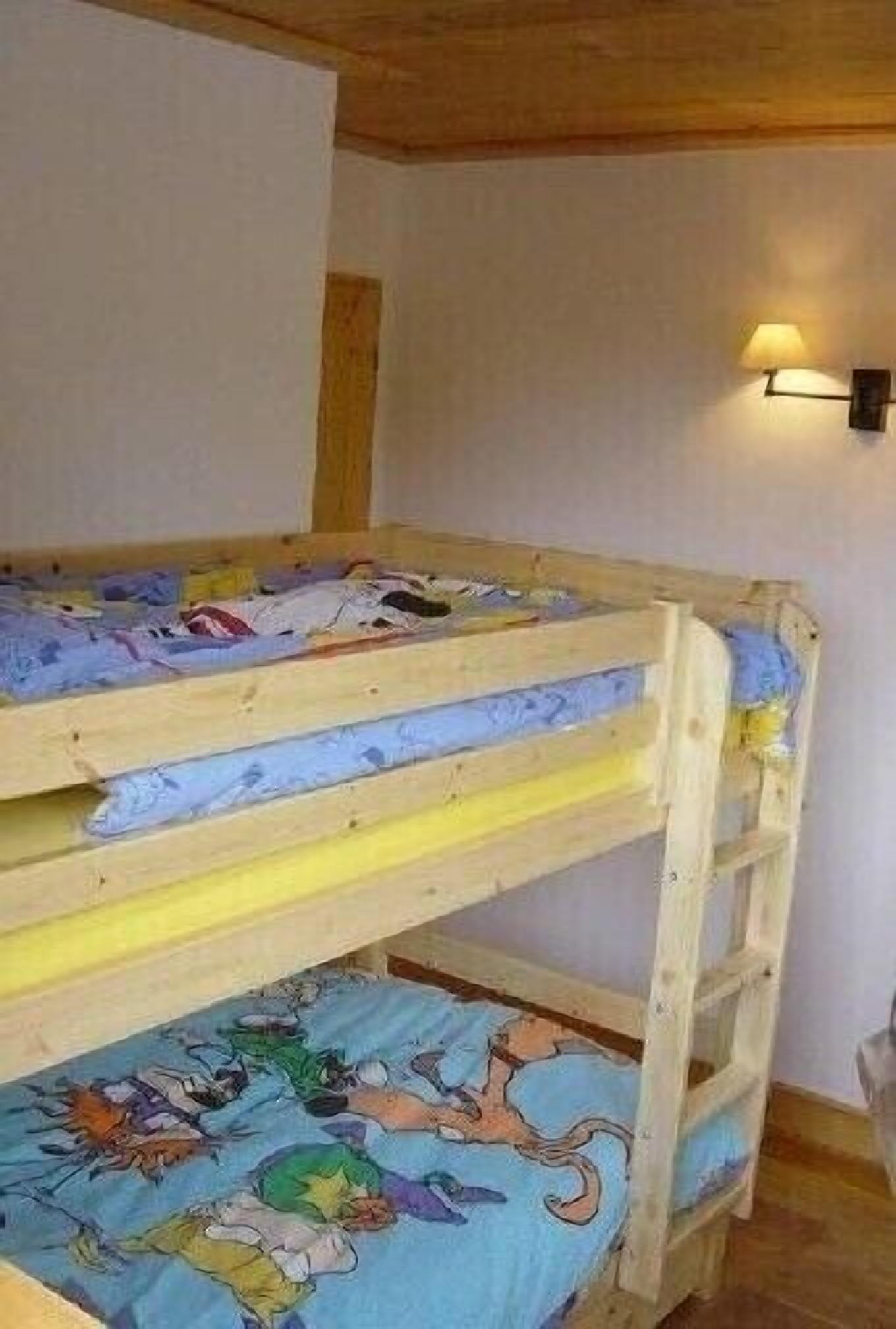 A bunk bed with a colorful bedspread and a wall-mounted light fixture.