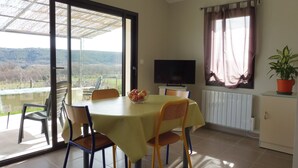 Ein Essbereich mit Tisch, Stühlen, einem Fernseher und Blick ins Freie.