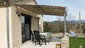 Eine Terrasse mit Tisch und Stühlen, eine Steinmauer und Blick auf die umliegende Landschaft.