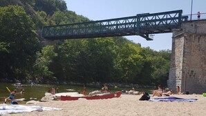 Ein Strand mit Booten, einer Brücke und einem Steinhaus.