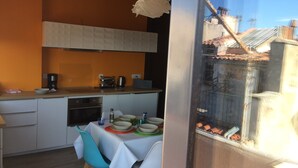A modern kitchen with white cabinets, a coffee maker, and a toaster. There is a dining table with chairs and a window overlooking a residential area. - BASKET 38+ 10m2 terrace facing the sea and Major / 4 PLACES 300mMUCEM, 800mVIEUX-PORT (Marseille)