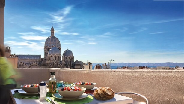 A table with food and a bottle, overlooking a historic building with domes. - BASKET 38+ 10m2 terrace facing the sea and Major / 4 PLACES 300mMUCEM, 800mVIEUX-PORT (Marseille)