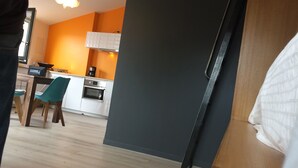 A modern kitchen with white cabinets, a black countertop, and a coffee maker. There is a dining area with a wooden table and teal chairs. - BASKET 38+ 10m2 terrace facing the sea and Major / 4 PLACES 300mMUCEM, 800mVIEUX-PORT (Marseille)