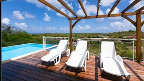 A wooden deck with a pool, three white lounge chairs, and a view of a green landscape. - Calm, Serenity and Charm will seduce you .... (Sainte-Anne)