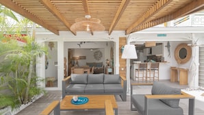 Un espacio al aire libre moderno con techo de madera, un sofá gris y una mesa de madera.