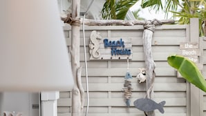 Una valla de madera con un letrero que dice 'Beach House' y peces decorativos.