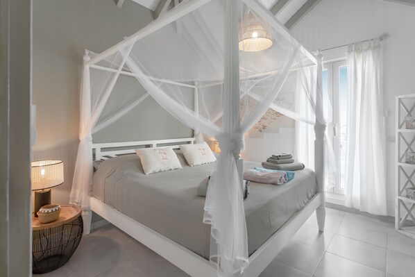 A four-poster canopy bed with a white finish, a bedside table with a lamp, and a view of the outdoors through a window with sheer curtains. - ✨ villa beach house 150 m from Orient Bay beach a stone's throw from restaurants🌴 (saint martin)