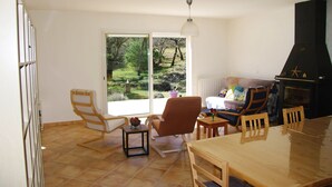 Un espacio habitable amplio con un gran ventanal, chimenea y mesa de comedor.