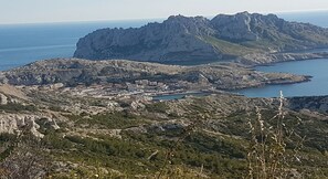 A coastal town with rocky terrain, a small harbor, and a prominent mountain in the background.