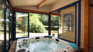 Un bain à remous avec vue sur un jardin, grâce à de grandes fenêtres.