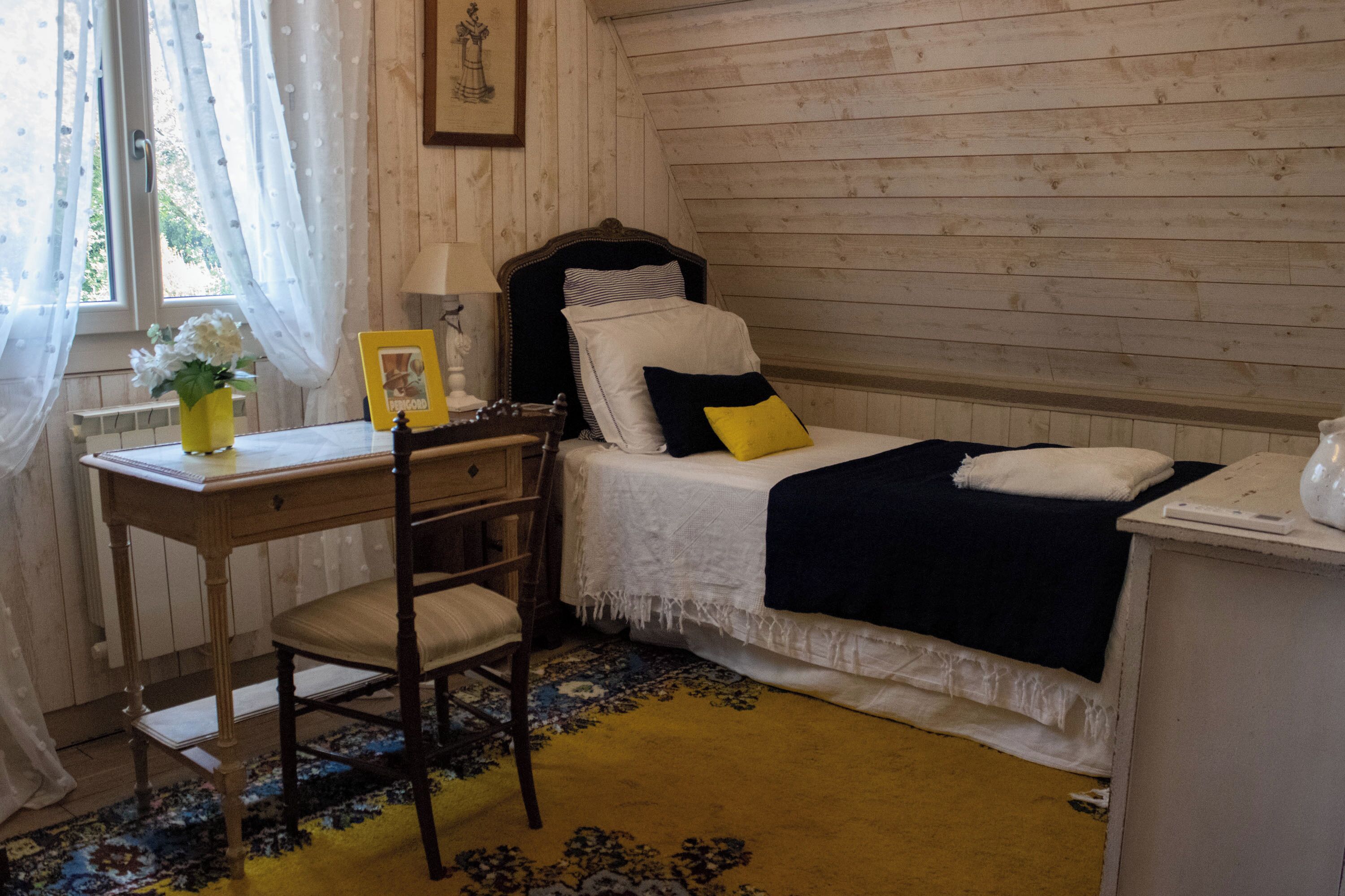 Ein Schlafzimmer mit einem Einzelbett, einem Schreibtisch und einem Stuhl.