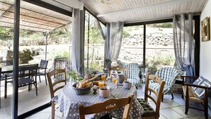 Un espace de restauration en plein air, avec une table dressée pour le petit-déjeuner, entourée de chaises et offrant une vue sur le jardin.