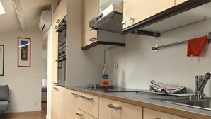 Eine moderne Küche mit Spüle aus Edelstahl, Holzschränken und einem eingebauten Backofen.